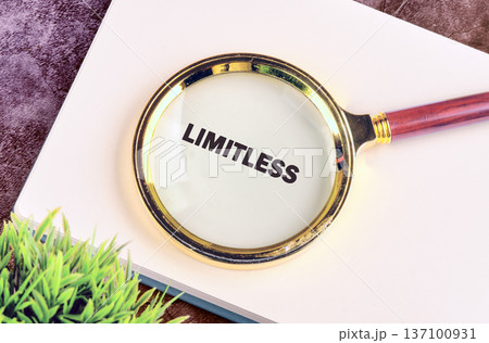 A sleek magnifying glass highlights the powerful word Limitless on a crisp white notebook, suggesting infinite potential and growth on a quiet desk A sleek magnifying glass highlights the powerful word Limitless on a crisp white notebook, suggesting infinite potential and growth on a quiet desk 137100931