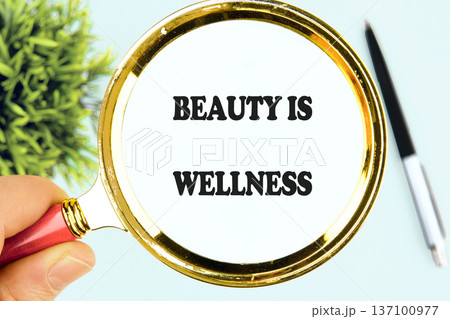 A human hand holds a gleaming magnifying glass, focusing on the powerful message Beauty Is Wellness A human hand holds a gleaming magnifying glass, focusing on the powerful message Beauty Is Wellness 137100977