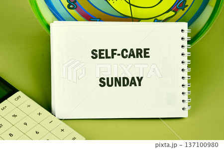 White notepad on lime green says Self-Care Sunday, encouraging wellness. Calculator nearby White notepad on lime green says Self-Care Sunday, encouraging wellness. Calculator nearby 137100980