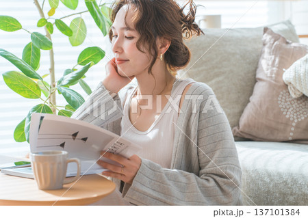 リビングで雑誌を読むオシャレなアジア人女性 137101384