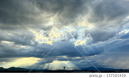 天使の梯子：厚い雨雲の隙間から街や山並みに向かって放射状に降り注ぐ光の筋が神々しく美しい絶景 137101410