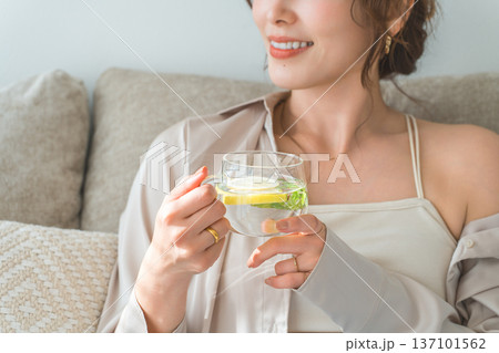 ソファーに座りレモン水,デトックスウォーターを飲む女性 ソファーに座りレモン水,デトックスウォーターを飲む女性 137101562