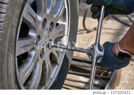 Repair car service.Wheel mounting.Worker tightens nuts on wheel 137102421