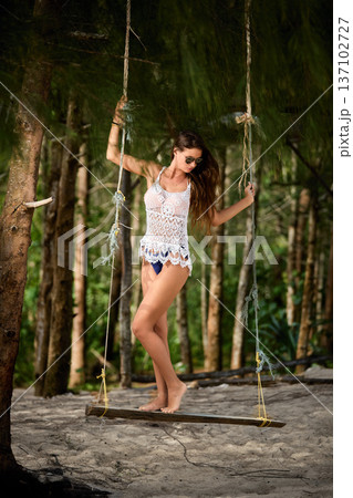 Tropical forest swing portrait of elegant woman in beachwear Tropical forest swing portrait of elegant woman in beachwear 137102727