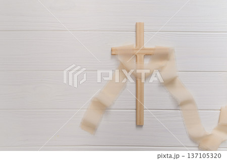 Wooden cross symbolizing christian faith and spirituality, delicate ribbon on a clean copyspace background remembrance for easter Wooden cross symbolizing christian faith and spirituality, delicate ribbon on a clean copyspace background remembrance for easter 137105320