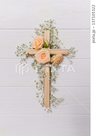 Vertical Wooden cross decorated with gypsophila flowers on a white background for easter and good friday celebrations copyspace 137105322