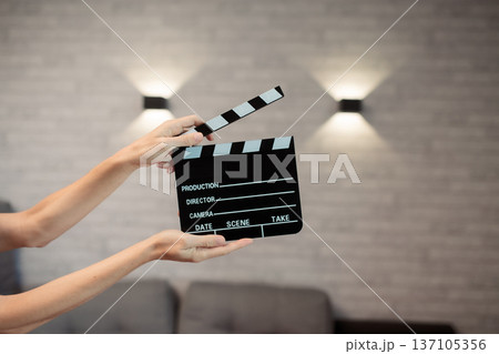 Hands holding clapperboard, signaling start of film production, cinematic movie making storytelling, industry concept 137105356