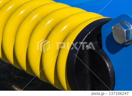 Steel yellow spring as part of heavy agricultural, industrial machine. Technology 137106247