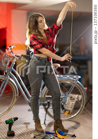 Young woman measuring bike components in garage Young woman measuring bike components in garage 137106560