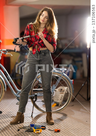 Woman repairing bicycle part with screwdriver in garage Woman repairing bicycle part with screwdriver in garage 137106563