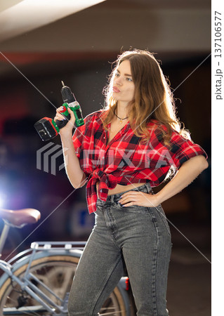 Young woman confidently holding power drill demonstrating diy skills 137106577