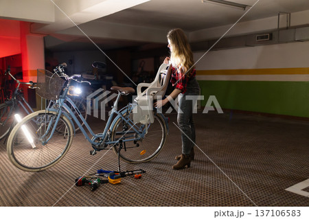 Woman attaching a child seat to a bicycle for family ride 137106583