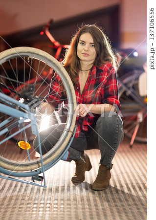 Young woman repairing bicycle wheel working in workshop 137106586