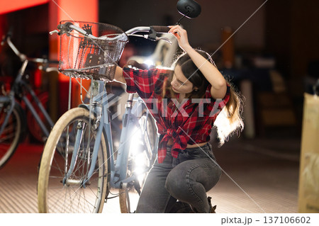 Woman repairing light blue bicycle in workshop Woman repairing light blue bicycle in workshop 137106602