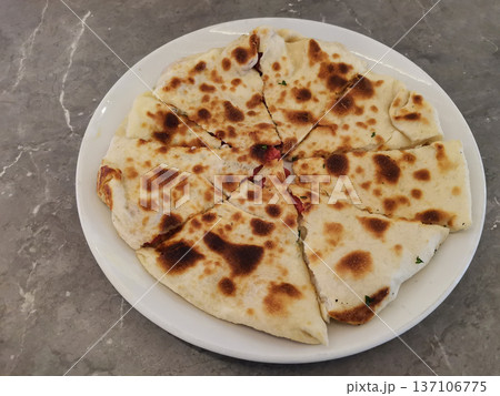 Sliced toasted stuffed flatbread on white plate for menu background and food presentation for restaurant appetizer and casual dining 137106775