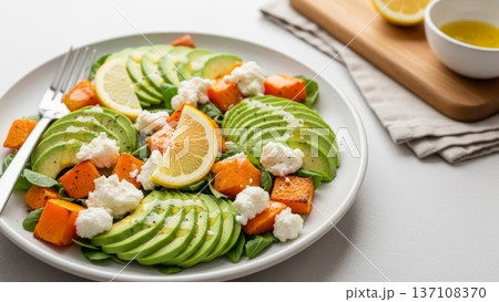 Sliced avocado and roasted squash salad with lemon wedges and ricotta for healthy menu layout and food banner design Sliced avocado and roasted squash salad with lemon wedges and ricotta for healthy menu layout and food banner design 137108370