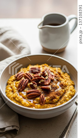 Closeup pumpkin porridge with pecans and maple syrup pitcher for autumn breakfast recipe and cozy bowl background Closeup pumpkin porridge with pecans and maple syrup pitcher for autumn breakfast recipe and cozy bowl background 137108391