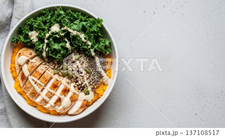 Overhead kale and grilled chicken bowl with creamy dressing and sweet potato puree for healthy recipe background and blog header image 137108517
