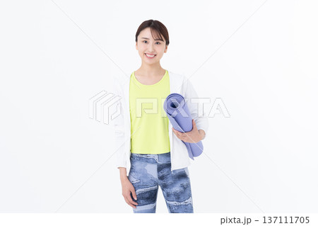 ヨガマットを持つ若い女性 137111705