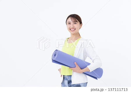 ヨガマットを持つ若い女性 137111713