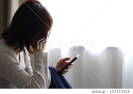スマホを見て悩む女性の横顔 137113324