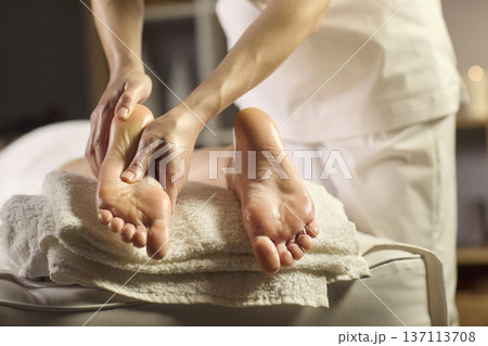 Close up therapeutic foot massage in spa with therapist hands and candles Close up therapeutic foot massage in spa with therapist hands and candles 137113708