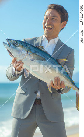 大物を釣り上げたビジネスマン 海辺で喜ぶ男性 137114669