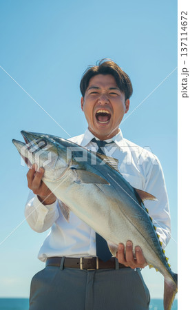 大物を釣り上げたビジネスマン 海辺で喜ぶ男性 137114672