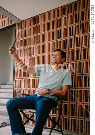 Casual Man Taking a Selfie with Smartphone Against Modern Wall Casual Man Taking a Selfie with Smartphone Against Modern Wall 137114783
