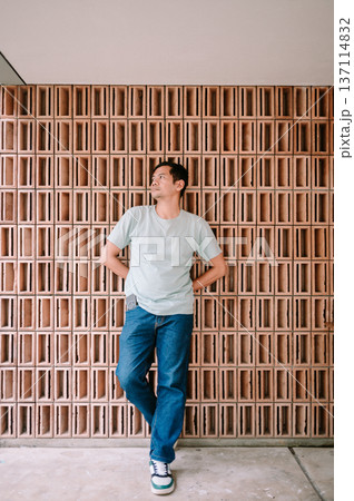 Casual Man Posing Against Modern Terracotta Brick Wall Casual Man Posing Against Modern Terracotta Brick Wall 137114832