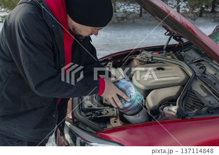 Man pours liquids under the hood of a car. antifreeze, water, washer fluid. red car. close up photo Man pours liquids under the hood of a car. antifreeze, water, washer fluid. red car. close up photo 137114848
