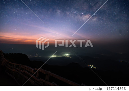 Beautiful twilight sky with stars over a mountain ridge trail and wooden fence at dawn. 137114868