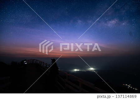 Beautiful twilight sky with stars over a mountain ridge trail and wooden fence at dawn. 137114869
