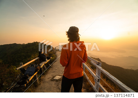 Male traveler and drone pilot operating remote controller on mountain peak during sunrise. 137114871