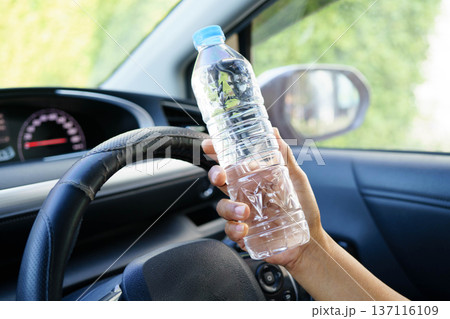 Asian woman driver holding water bottle in car. Asian woman driver holding water bottle in car. 137116109