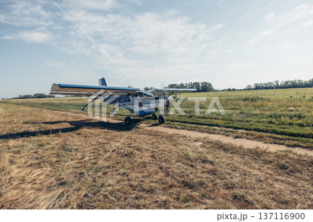 small propeller airplane moving along countryside airstrip near farm fields with open horizon and large copy space for text outdoor scene concept of rural aviation, farming, agricultural industry 137116900