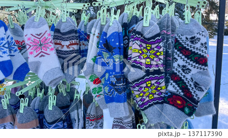 Traditional wool knitted socks with ornaments hanging at a winter street market as seasonal souvenirs. 137117390