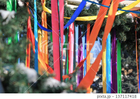 Spring festival arch made of evergreen branches decorated with many long colorful ribbons outdoors. Spring festival arch made of evergreen branches decorated with many long colorful ribbons outdoors. 137117418