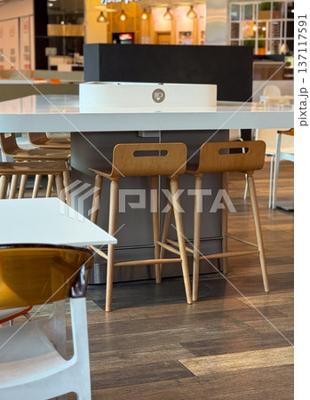 Empty chairs and tables in a modern food court create a calm and inviting atmosphere for visitors. Social interaction, hospitality, dining culture and contemporary lifestyle within an urban commercial Empty chairs and tables in a modern food court create a calm and inviting atmosphere for visitors. Social interaction, hospitality, dining culture and contemporary lifestyle within an urban commercial 137117591