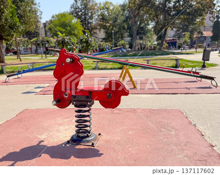 Red spring rider on the playground. Fun, balance and childhood activity in an outdoor park. Red spring rider on the playground. Fun, balance and childhood activity in an outdoor park. 137117602