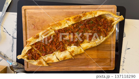 Fresh pide sliced on wooden board. Lunch meal, comfort food, Turkish cuisine tradition, dining moment and homemade baked serving. Fresh pide sliced on wooden board. Lunch meal, comfort food, Turkish cuisine tradition, dining moment and homemade baked serving. 137118290