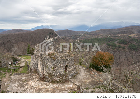 Anakopia fortress stone tower ruins with mountain panorama and distant snowfall over forest landscape in Abkhazia. Image supports travel marketing, adventure tourism promotion and heritage destination 137118579