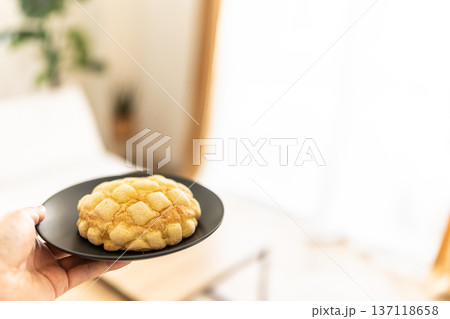 皿に載ったメロンパンを持つ。 皿に載ったメロンパンを持つ。 137118658