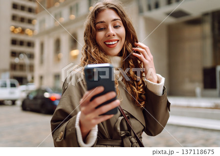 Happy female browsing internet in smartphone while standing on street. Lifestyle, travel, technology Happy female browsing internet in smartphone while standing on street. Lifestyle, travel, technology 137118675