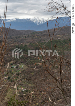 Mountain valley landscape with winding roads and rural houses viewed from Anacopia fortress in Abkhazia with snowcapped peaks in background, Scenic panorama suitable for travel marketing Mountain valley landscape with winding roads and rural houses viewed from Anacopia fortress in Abkhazia with snowcapped peaks in background, Scenic panorama suitable for travel marketing 137118802