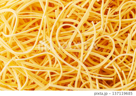 Dry egg noodles forming a tangled yellow background 137119685