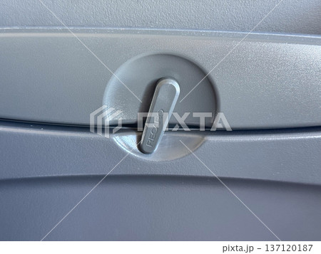 Airplane seat tray latch with safety marking in aircraft cabin interior. Aviation travel routine, passenger comfort, functional design, and everyday details of commercial flight experience. Airplane seat tray latch with safety marking in aircraft cabin interior. Aviation travel routine, passenger comfort, functional design, and everyday details of commercial flight experience. 137120187