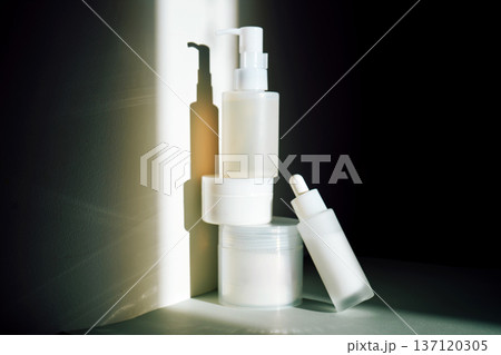Skincare product bottles creating shadows on minimalist background 137120305