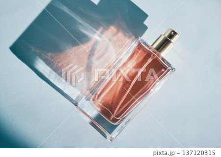 Perfume bottle creating aesthetic shadows and light patterns on light background 137120315
