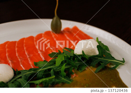 A plate with sliced red fish, bread and greens 137120436
